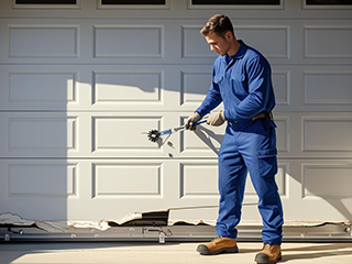 Technician in blue uniform repairing a damaged white garage door panel with specialized tools in Taylorsville, UT
