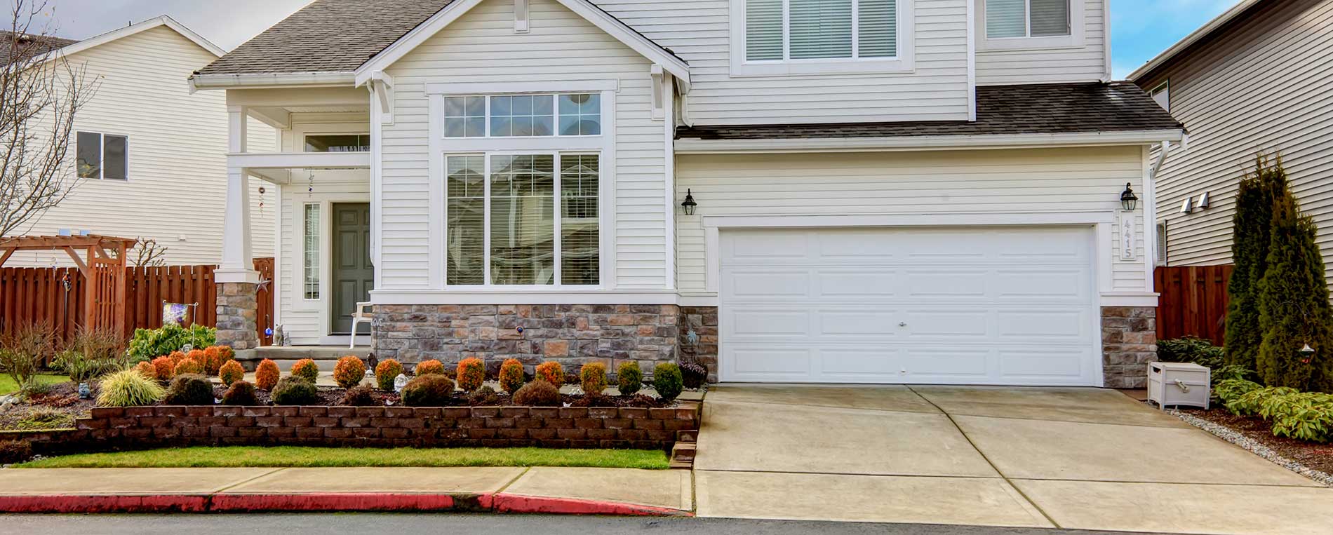 White two-story house with a double garage door and professional landscaping in Taylorsville, Utah