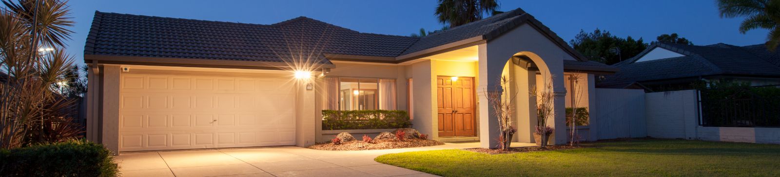Evening view of a Taylorsville home with a clean, well-lit garage door and tidy front yard.